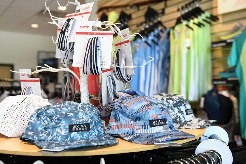 Image of the Mt Van Hoevenberg store showing Skida hats in  the foreground and SWIX apparel on the wall in the background. 