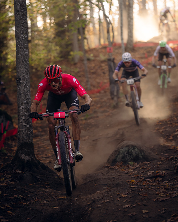 Image of 3 male mountain bike racers racing down a hill at the 2025 UCI MTB World Series at Mt Van Hoevenberg.