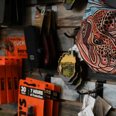 Items for sale on the wall at the Mt Van Hoevenberg wall including Buffs, big spray, and other camping supplies.