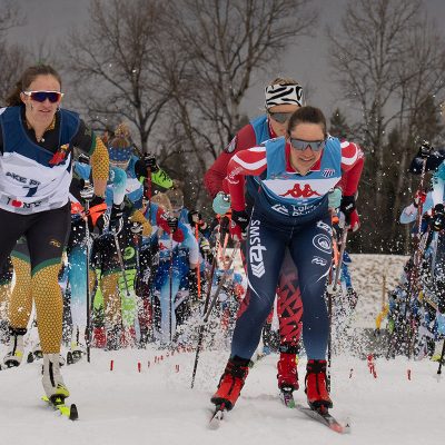 A group of cross-country ski racers begin in a pack at mt van hoevenberg.