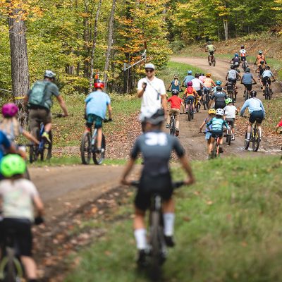 A large group of youth mountain bikers on a group ride during the fall.