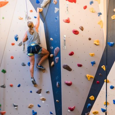 A woman is climbing while being belayed at Hi Notch Indoor Climbing at Mt Van Hoevenberg.